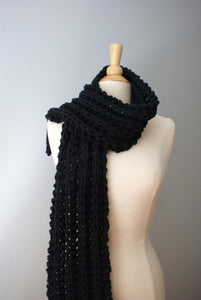 chunky scarf shown in black thrown over one shoulders